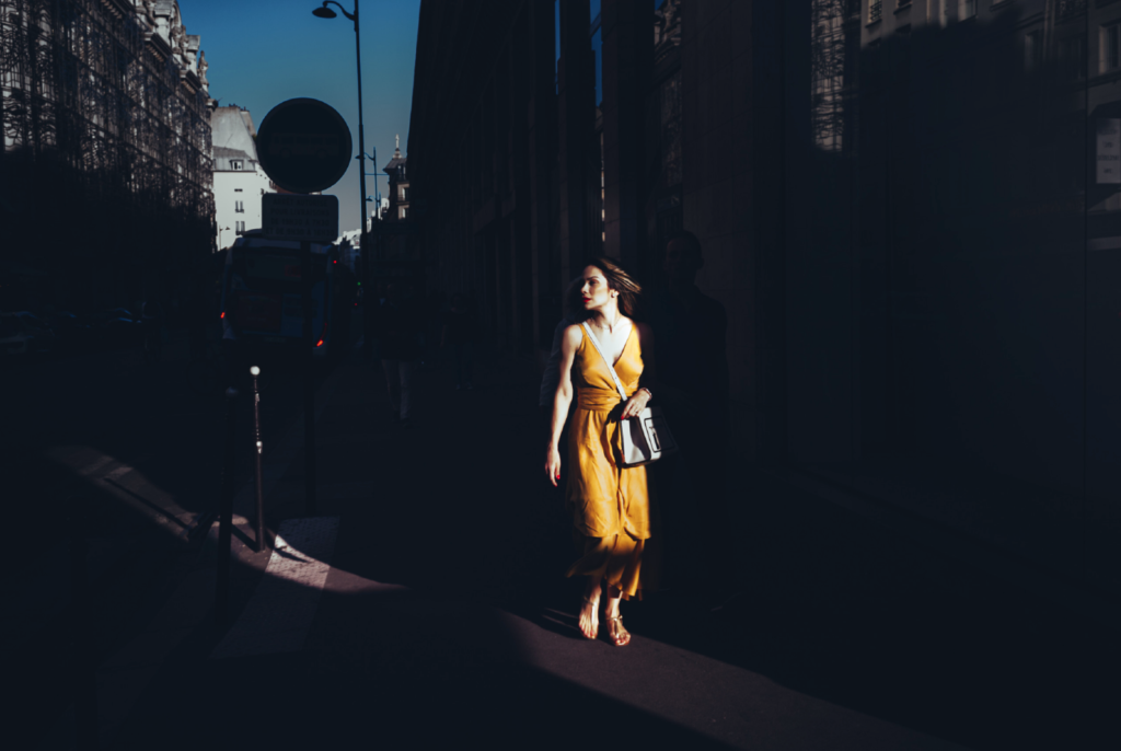 Femme en jaune traversant un rayon lumineux dans une photographie d’Hervé Chatel