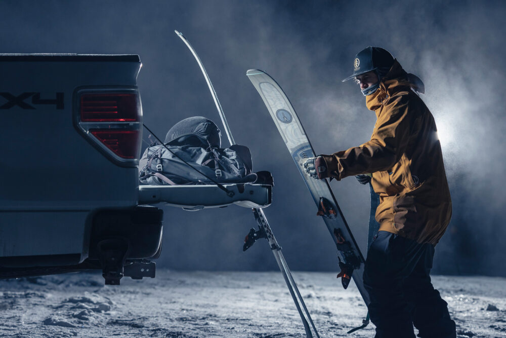 Skieur préparant son matériel sur le hayon d'un pick-up, éclairé par deux flashs Elinchrom